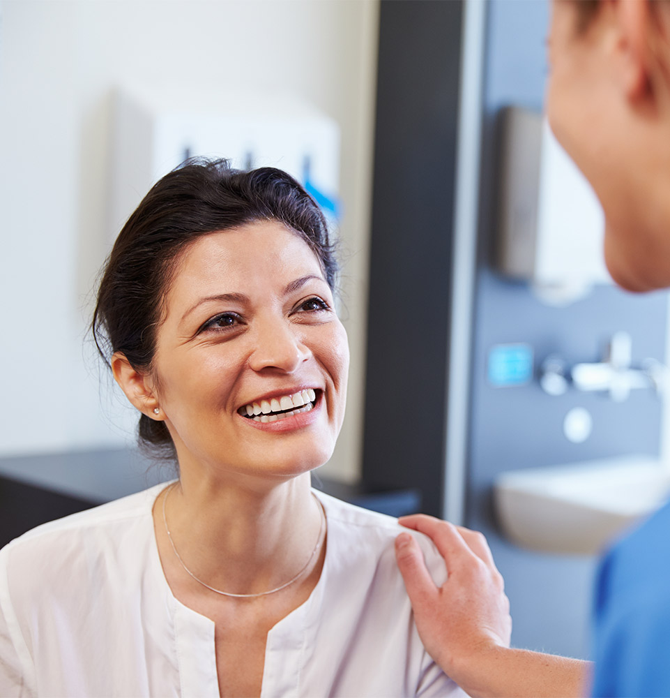 very nice lady smiling at assistant while assistant puts hand on patients shoulder