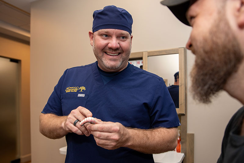 doctor showing dental implant model within the dental center for patient treatment