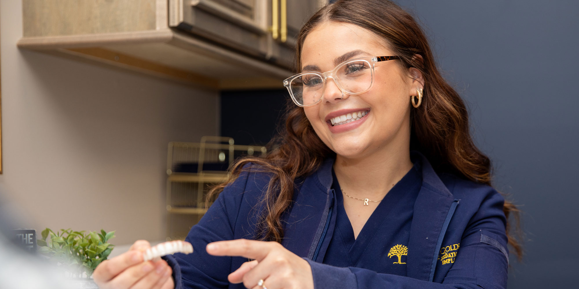 Team member holding a model of full arch dental implants
